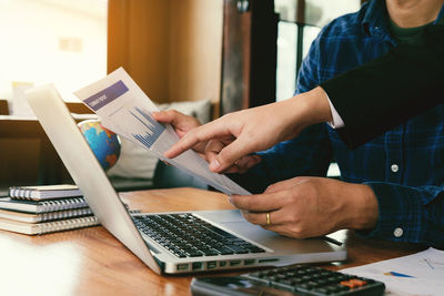 Midsection of man using laptop on table