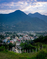 Aerial view of townscape by mountains against sky