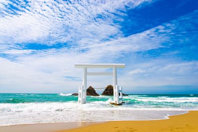 Lifeguard hut on beach against blue sky