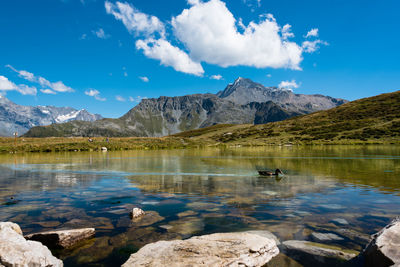 Scenic view of lake and mountains against blue sky