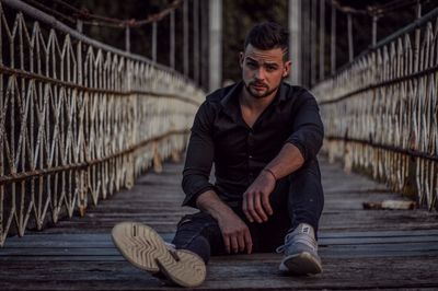 Young man sitting on railing in city