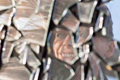 Reflection of cheerful woman on broken glass