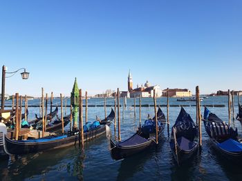 Boats moored in canal against clear blue sky