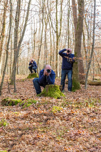 Multiple image of man photographing in forest during autumn