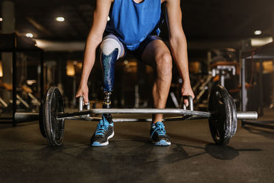 Low section of man with prosthetic legs exercising in gym