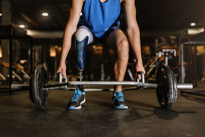Low section of man with prosthetic legs exercising in gym