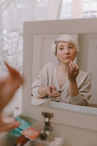 Portrait of a beautiful young woman holding mirror at home