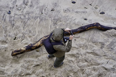 High angle view of man photographing with smart phone while standing land