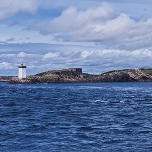 Lighthouse by sea against sky