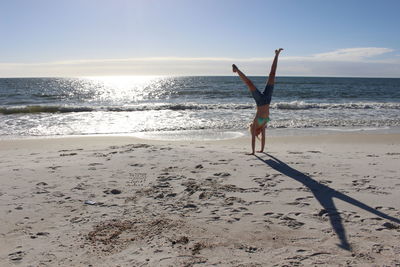 Woman doing cartwheel on sand at beach