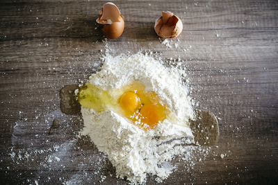 High angle view of eggs in flour on wooden table