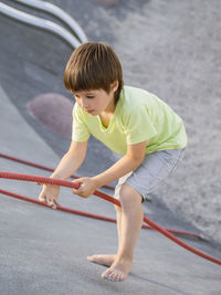 Boy climbes up a concrete slope of modern  sportsground. kid overcomes fear and learn new things. 