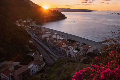 High angle view of sea and buildings against sky during sunset