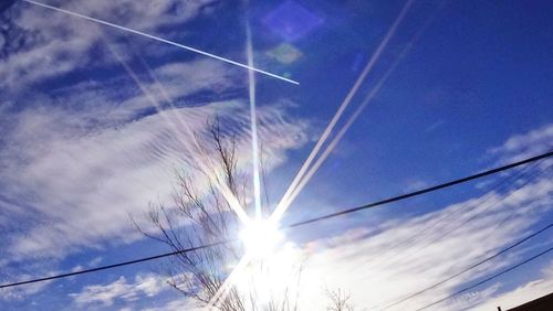 Low angle view of sun shining through clouds