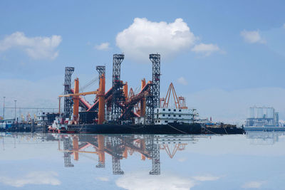 Cranes at commercial dock against sky