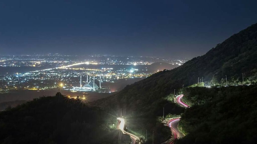 HIGH ANGLE VIEW OF ILLUMINATED LANDSCAPE AGAINST SKY