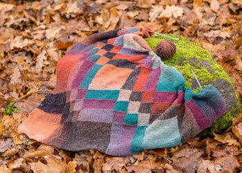 Beautiful and colorful entrelac style knitted scarf on the ground background, handicrafts