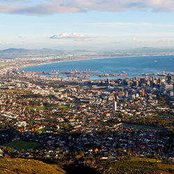 High angle view of illuminated city by sea against sky