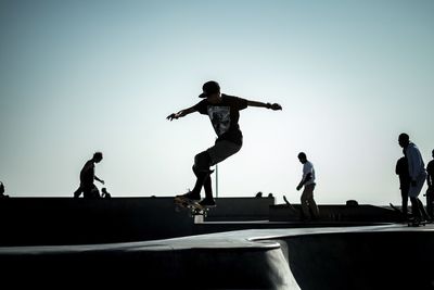 Man skateboarding in park against clear sky on sunny day