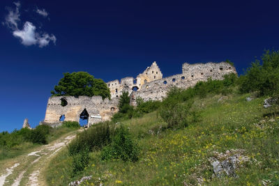 Low angle view of castle on mountain against sky