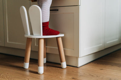 Low section of girl standing on chair at home