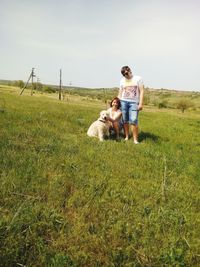 Full length of woman walking with dog on field