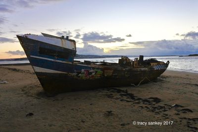 Boat moored on beach against sky