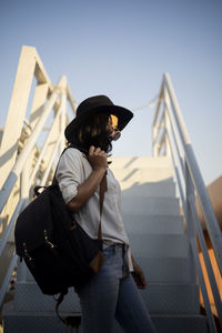 Young woman standing by steps against sky