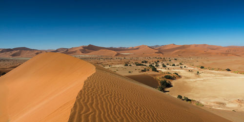 Scenic view of desert against clear blue sky