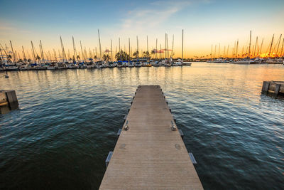 Sailboats moored on sea against sky during sunset