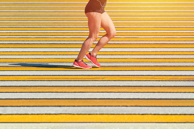 Woman running crosswalk, copy space. athletic woman jogging in sportswear on city road