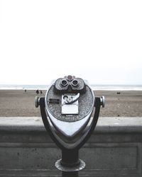 Coin-operated binoculars at beach against clear sky