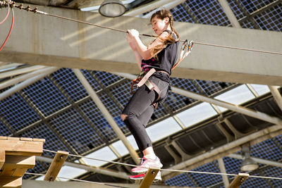 Low angle view of teenage girl walking on rope