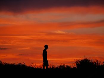 Silhouette of boy against cloudy sky at dusk