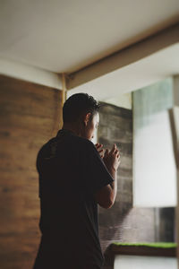 Side view of young man looking through window