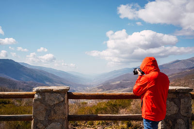 Unrecognizable photographer taking photos of the mountains with a blue sky with some clouds
