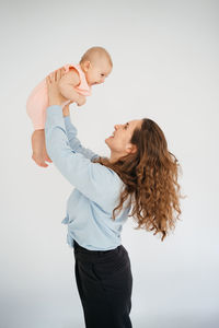 Young mother with long hair and in a shirt holds a newborn daughter. in the arms of a 6 month old 