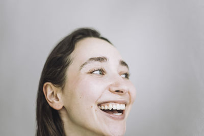 Happy female fashion designer looking away against gray background