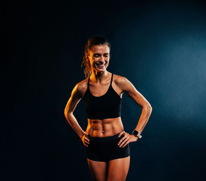 Smiling female athlete against black background