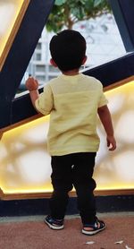 Rear view of boy standing by car