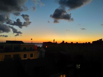 Exterior of silhouette buildings in town against sky during sunset