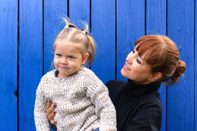 Happy and smiling mother middle aged woman holding child daughter on hands