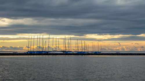 Sailboats in sea against sky during sunset