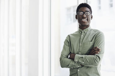 Portrait of smiling young man standing against wall