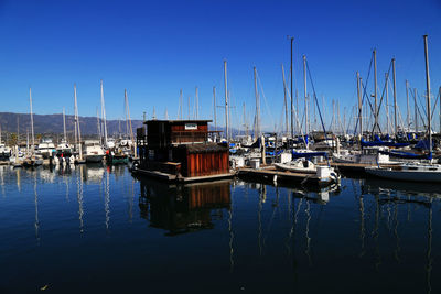 Boats moored in calm sea against clear blue sky