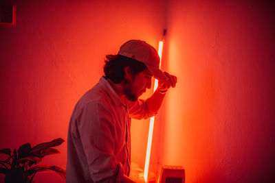 Side view of bearded man wearing cap in illuminated room