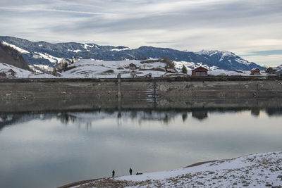 Scenic view of lake by snowcapped mountains against sky