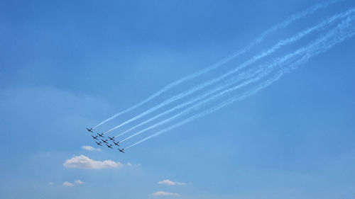 Low angle view of airshow against blue sky