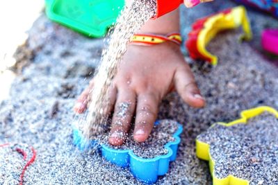 Cropped hand of girl playing with toys and sand