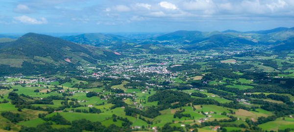 Aerial view of green landscape and mountains against sky